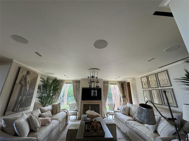 Salon avec enceintes encastrées au plafond et téléviseur au-dessus de la cheminée